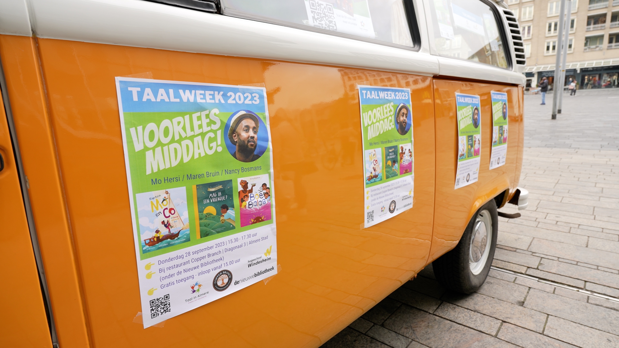 oranje Volkswagen bus met posters van de taalweek